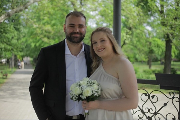 femeie blonda cu buchet de flori albe langa sotul ei
