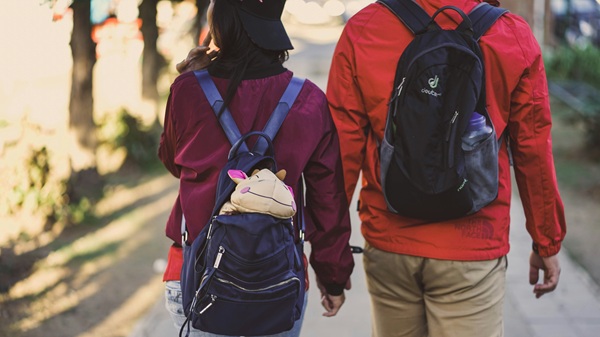 doi adolescenti cu ghiozdanul in spate se tin de mana