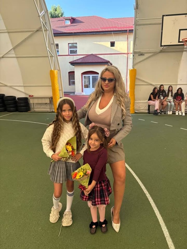 sanziana buruiana in costum gri cu fiicele ei cu flori in mana in prima zi de scoala