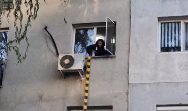 femeie se uita pe geam in jos