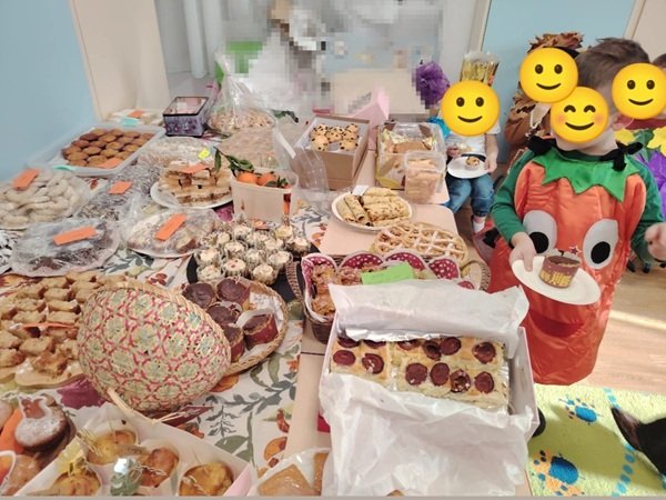 copii cu fetele acoperite langa o masa plina de bunatati