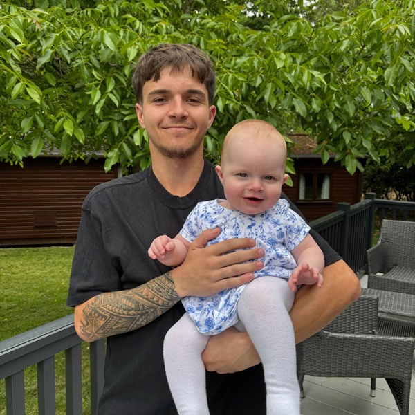 barbat in camasa neagra cu copil in brate