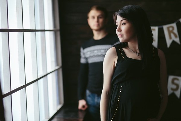 barbat in spatele unei femei insarcinate imbracata in negru