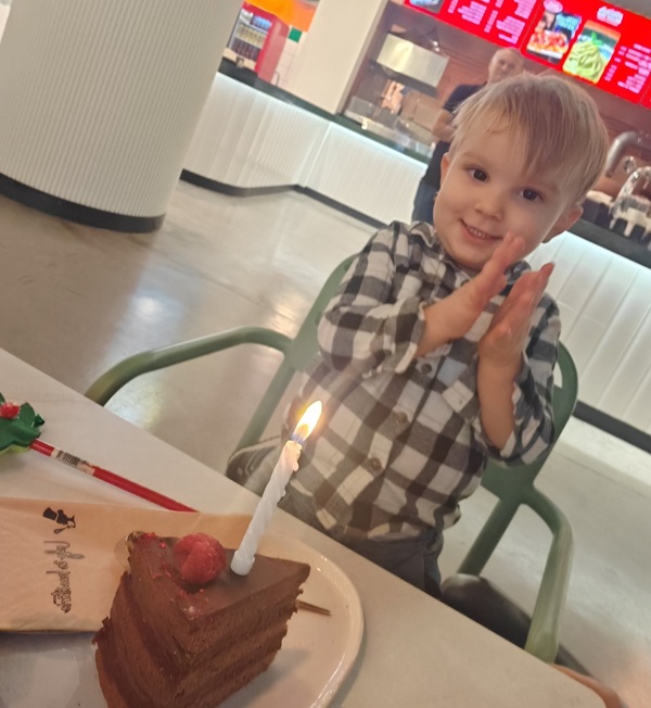 baiat blond se bucura la o prajitura cu o lumanare in ea