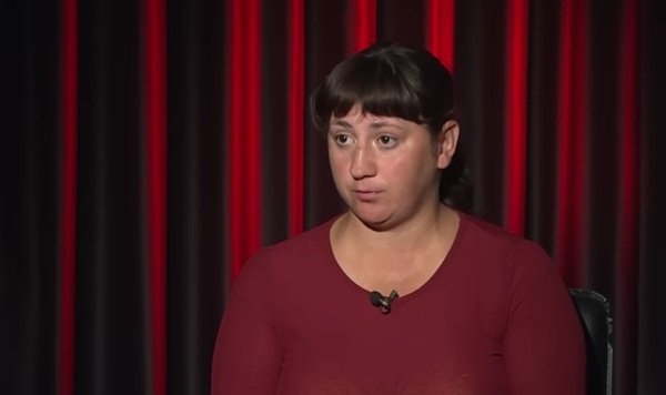 femeie cu parul saten prins imbracata in bluza grena