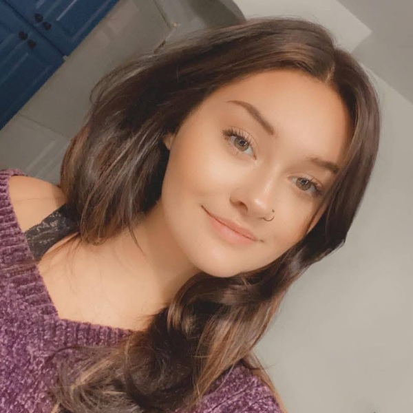 femeie cu parul saten lung si cercel in nas imbracata in mov