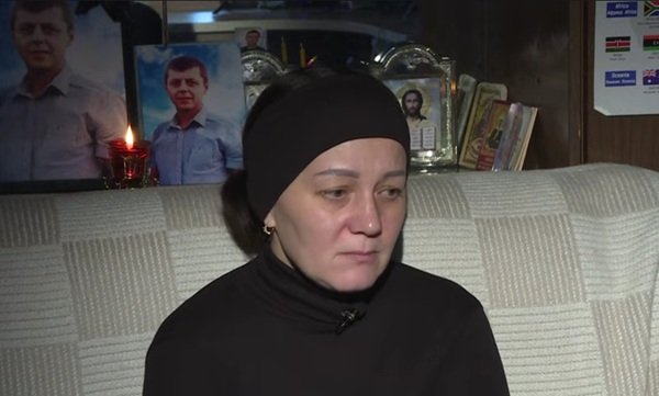 femeie imbracata in negru cu batic negru pe cap sta pe o canapea