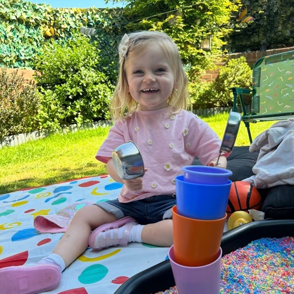 fata se joaca afara pe o patura