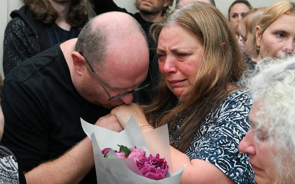 barbat si femeie plang si tin in mana un buchet de flori
