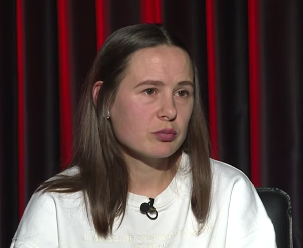 femeie cu parul saten mediu imbracata in alb pe fundalul unei cortine rosu visiniu