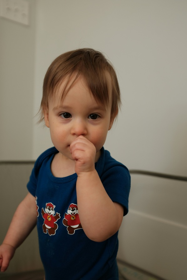 un copilas mic intr-un body albastru inchis isi suge degetul mare