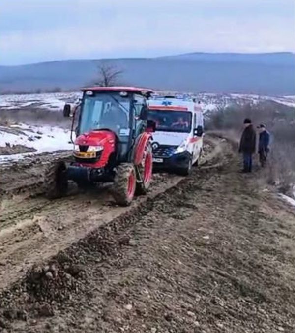 un tractor vechi trage o ambulanta pe un drum impracticabil ramasa impotmolita in noroi