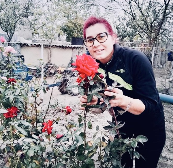 femeie imbracata in negru cu parul rosu si ochelari de vedere la ochi miroase trandafiri