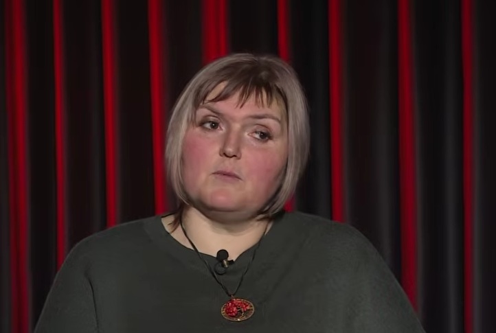 femeie blonda tunsa scurt cu parul drept pe fundal o copertina grena