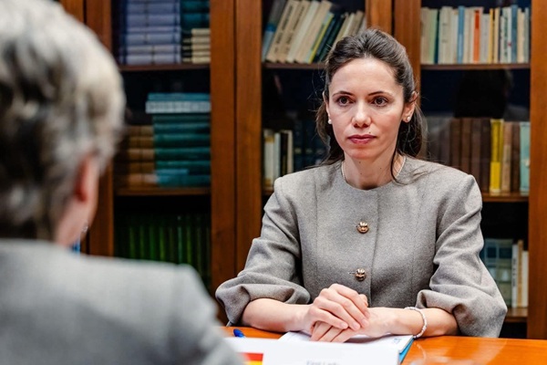 mirabela gradinaru in sacou gri cu parul prins pe fundal biblioyeca cu carti