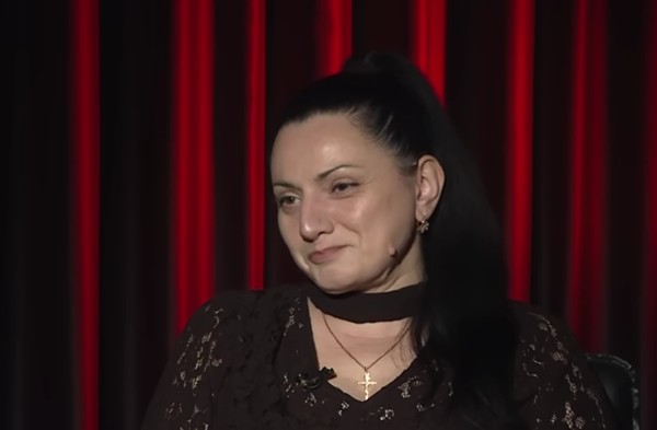 femeie cu parul brunet in bluza neagra da un interviu