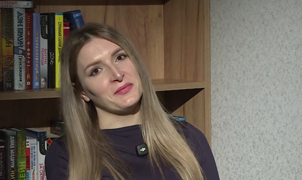 femeie cu parul lung blond imbracata in pulover gri cu capul intr o parte