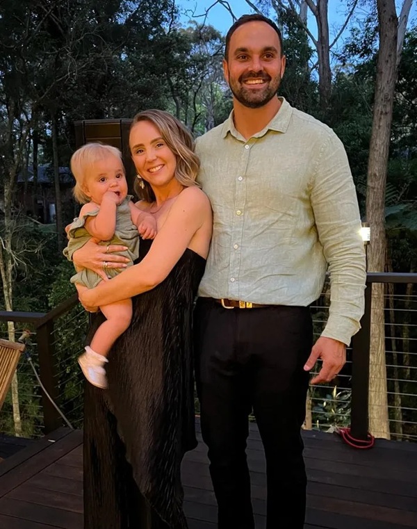 fotografie cu o mama care tine in brate un copil si tatal langa