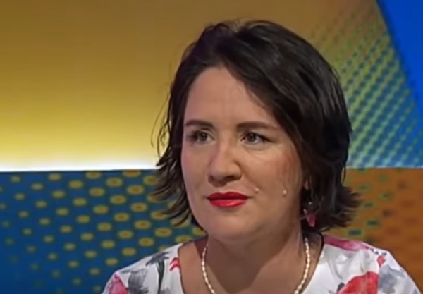 femeie bruneta cu parul pana la umeri cu ruj rosu imbracata in ie