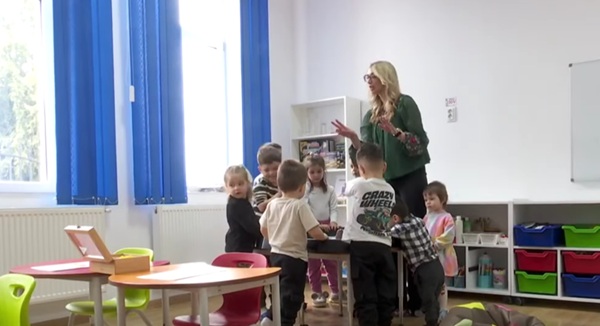 educatoare blonda cu parul lung inconjurata de copii