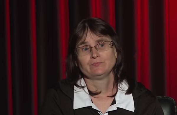 femeie in costum negru si camasa alba cu ochelari de vedere la ochi