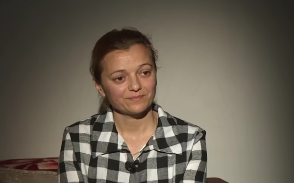 femeie cu camasa in carouri si parul prins in coada zambeste