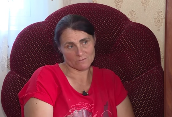 femeie satena cu parul prins in coada in tricou roz sta pe un fotoliu rosu