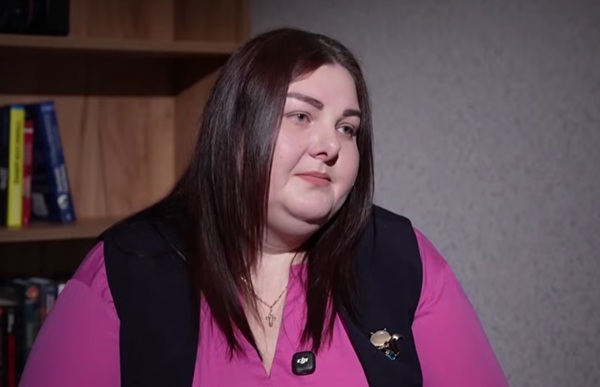 femeie satena cu parul lung in bluza roz cu un ilic negru