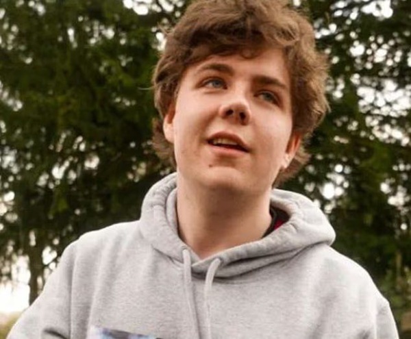 baiat cu parul mare si cret cu hanorac gri priveste in sus