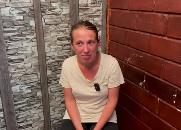 femeie cu parul prind cu un tricou alb si panataloni negri sta pe un scaun