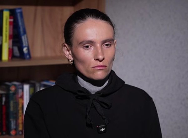 femeie bruneta cu parul prins imbracata in negru priveste in jos