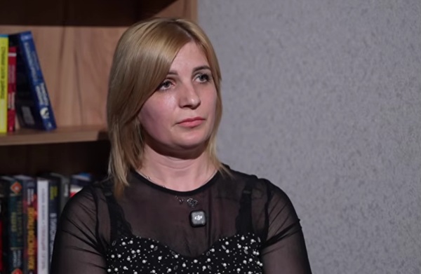 femeie blonda cu parul pana la umeri imbracata in bluza gri da un interviu