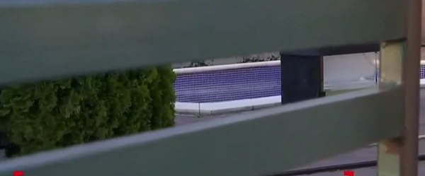 piscina aproape goala intr-o curte vazuta printr-un gard