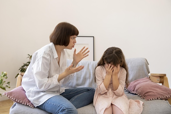mama suparata incearca sa ii spuna ceva fiicei ei gesticuland fiica sta cu capul pe genunchi