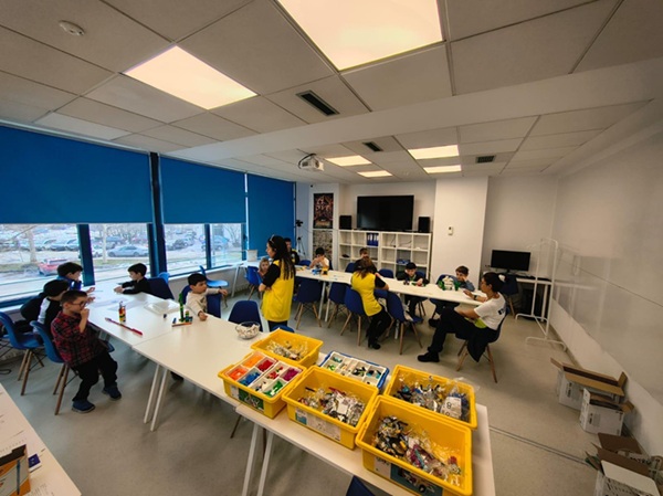 sala de clasa de robotica cu mai multi copii care lucreaza la diferite proiecte