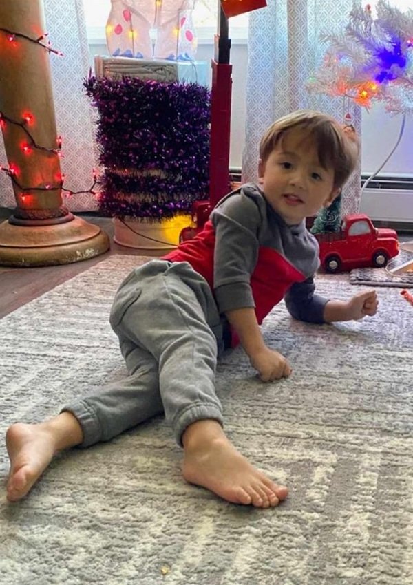 baiat in pijama sta intins pe jos langa bradul de craciun