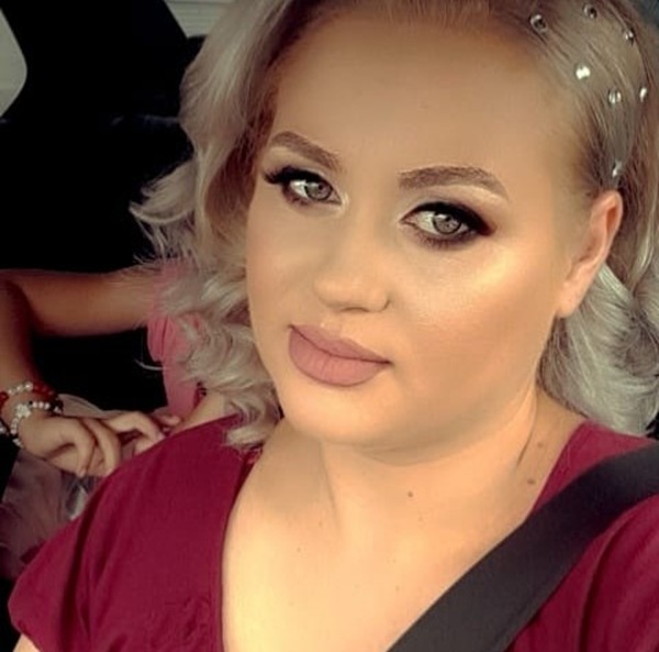 femeie machiata smokey eyes cu parul tapat blond imbracata in visiniu in masina