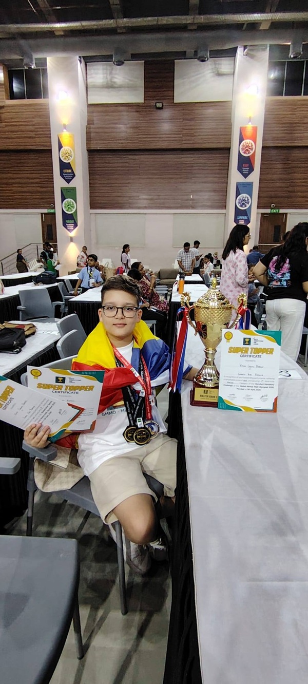 baiat sta la o masa si prezinta diplome si medalii