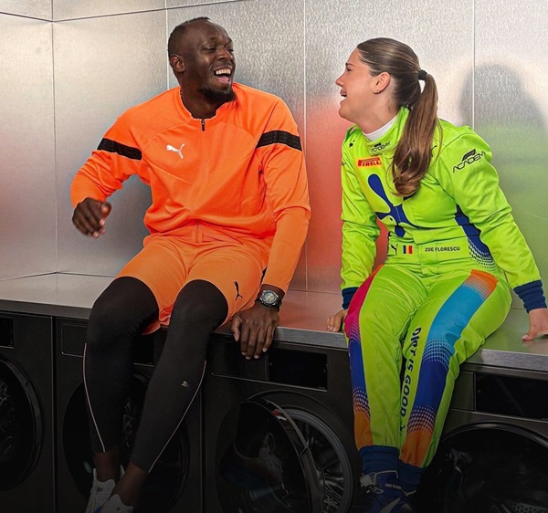 zoe florescu imbracata in verde alaturi de usain bolt imbracat in portocaliu rad impreuna si stau pe o masina de spalat rufe