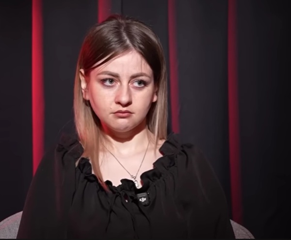 femeie cu parul blond pana la umeri imbracata in negru da un interviu