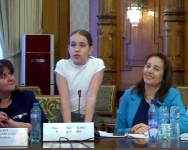 fata cu tricou alb tine un discurs inconjurata de mai multe doamne