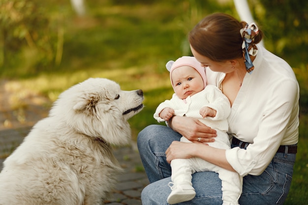 o mama tine un copil in brate langa un caine in parc