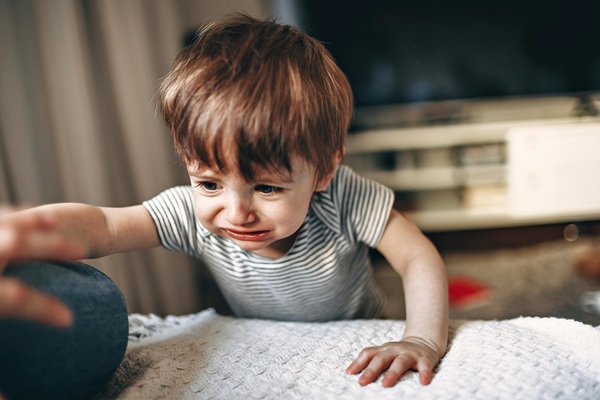 baiat in body gri plange sta la o masa si apuca un adult de maneca
