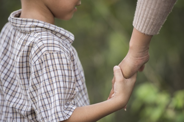 baiat in camasa movalie cu carouri tine de mana un adult