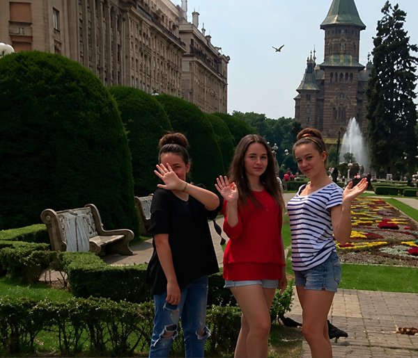 trei fete triplete fac cu mana la camera intr-un parc