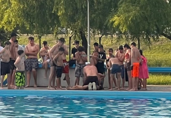 mai multe persoane stranse in jurul unui copil la piscina