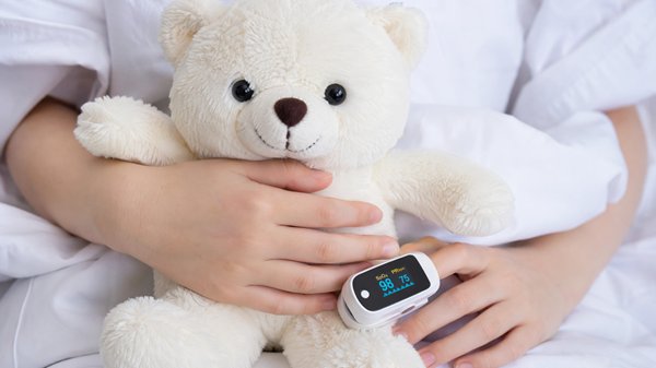 copil pe un pat de spital tine un ursulet in brate