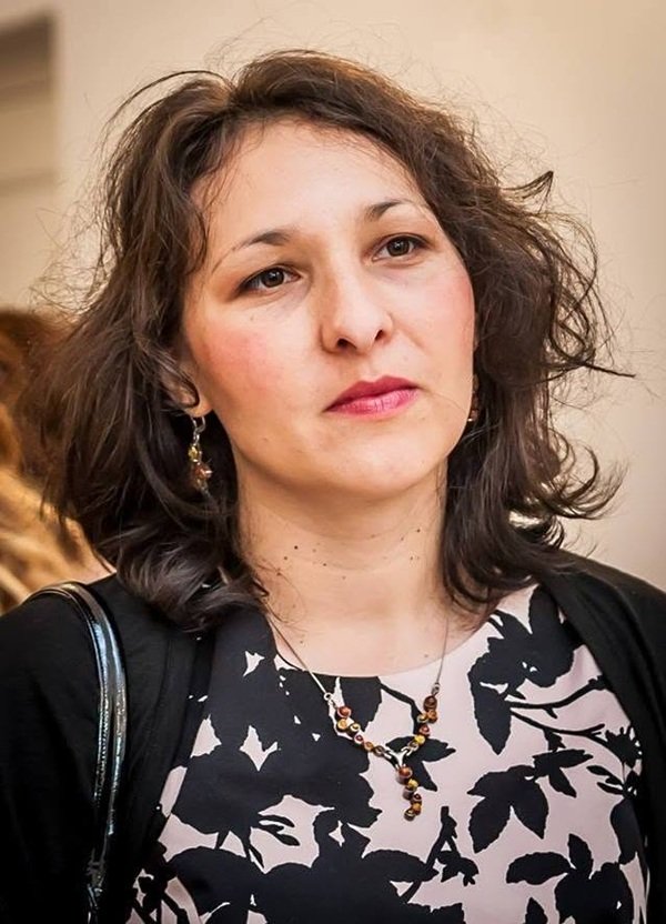 femeie cu parul mediu creț si bluza cu modele pe ea