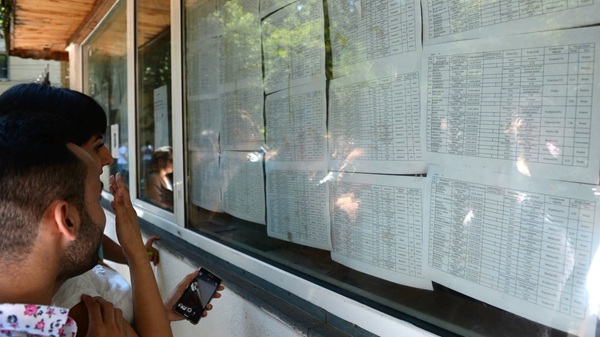 o fata si un baiat se uita pe liste afisate cu rezultatele la bac