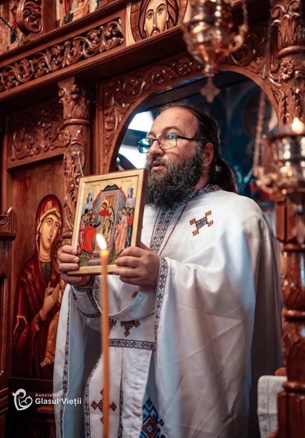 parintele dan damaschin in biserica tine mana o icoana sfanta langa altar